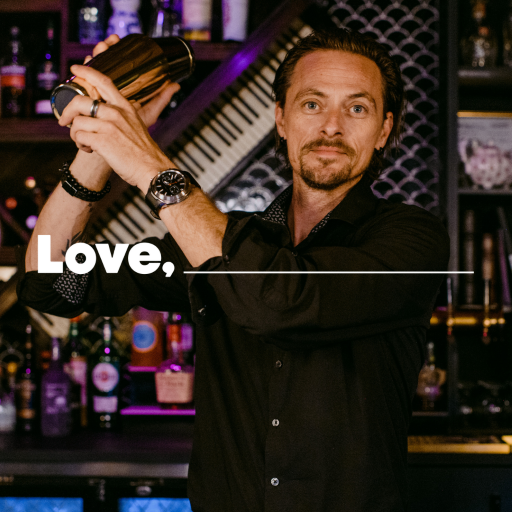 Man standing behind a bar shaking a cocktail